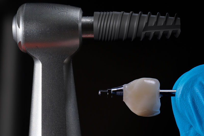 a tooth being held up next to a drill for dental implants to be placed